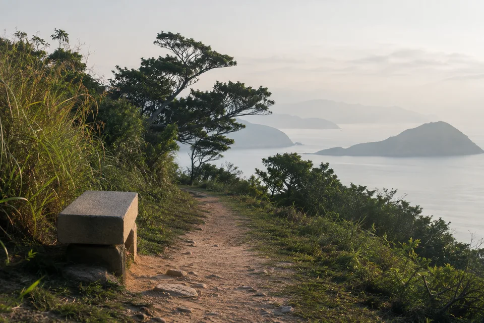 A quiet Hong Kong coastal path with a stone bench and distant islands